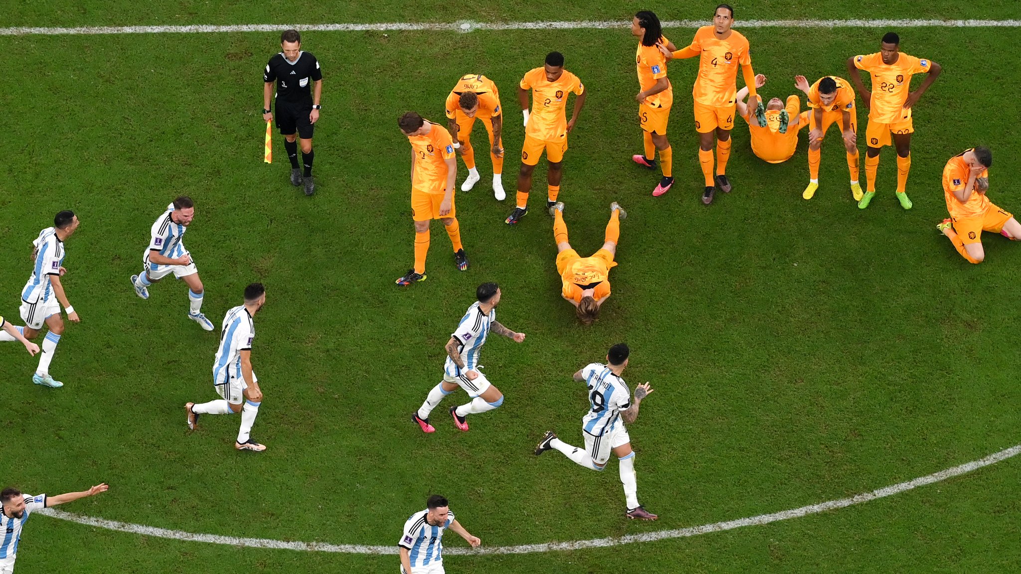 An aerial shot of Argentina's players celebrating in the face of dejected Netherlands players, some lying on the pitch, after winning their penalty shootout