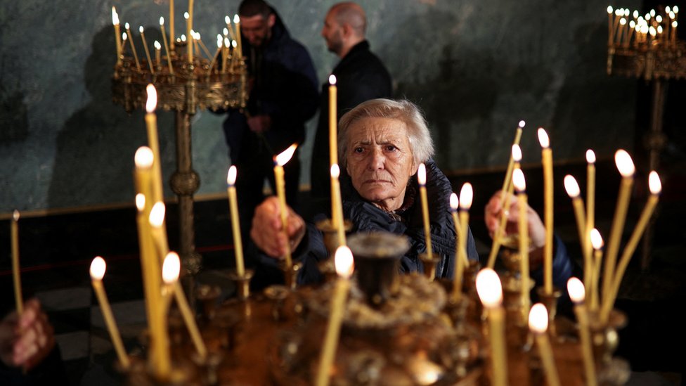 A woman lights a candle in a church in Bulgaria