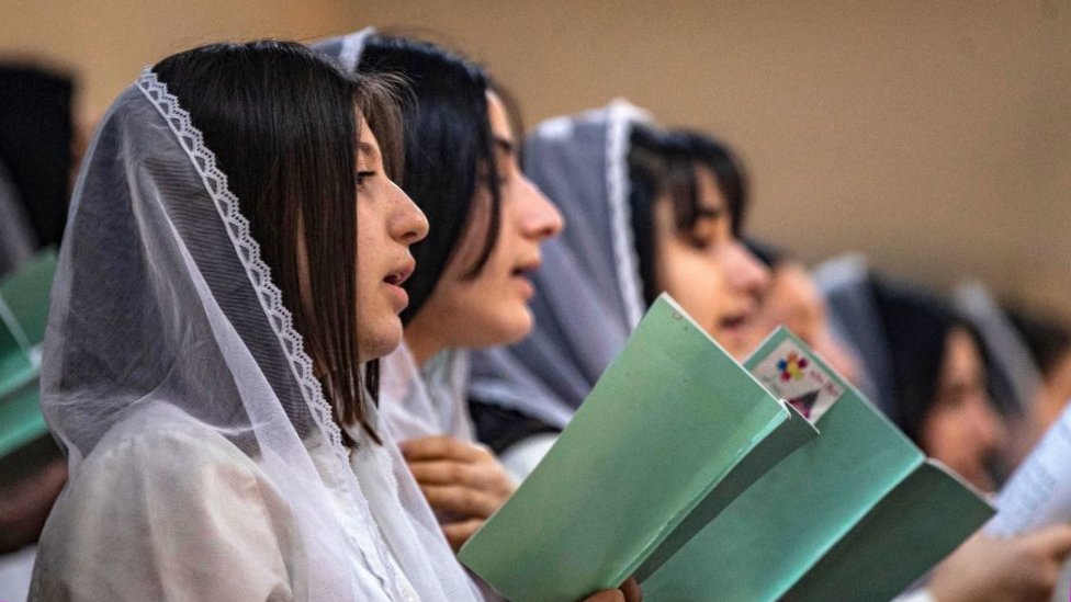Women worshippers chant during the Christmas morning mass in Qamishli, Syria