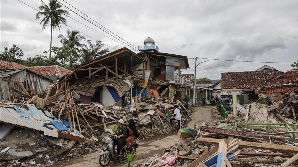 Motorists ride past collapsed houses affected by the 5.6 magnitude earthquake in Cianjur, West Java, Indonesia,