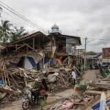 Motorists ride past collapsed houses affected by the 5.6 magnitude earthquake in Cianjur, West Java, Indonesia,