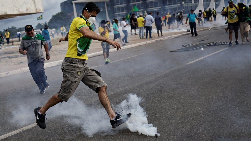 A demonstrator kicks a cannister of tear gas away outside Brazil's Congress building