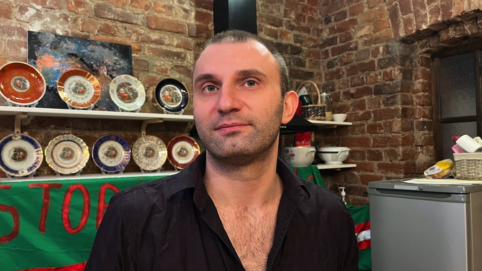 Piotr Voznesensky standing in front of shelves of ornamental plates