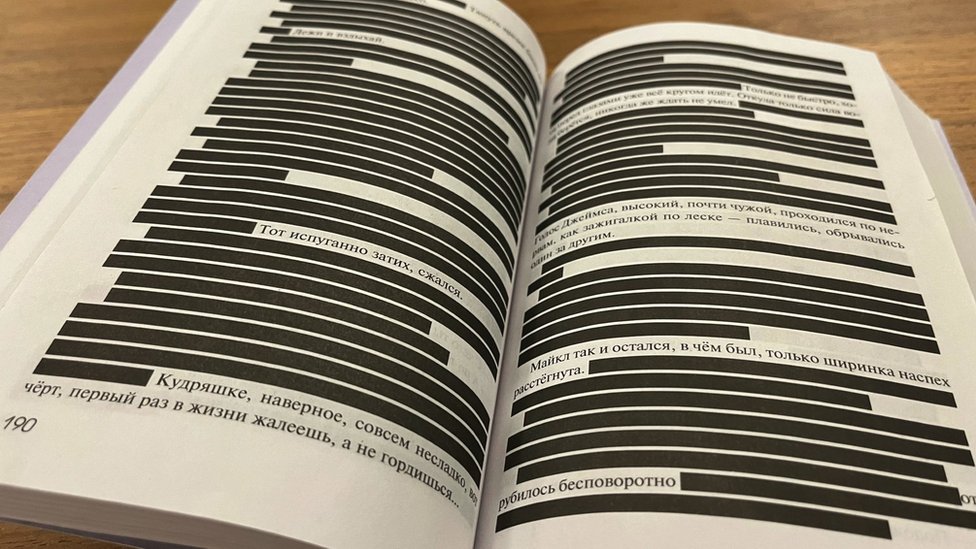 An open book with black bars obscuring most lines of text