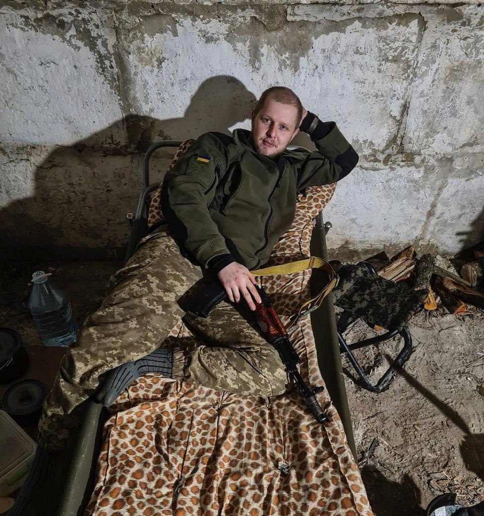 Andrii Kulibaba lying on a leopard skin blanket while wearing his uniform