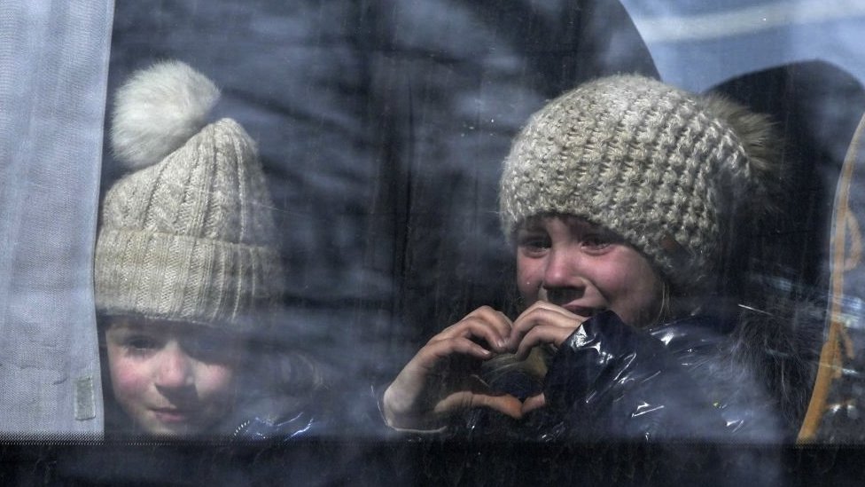 A little girl makes hearth shape with her hands as civilians are being evacuated along humanitarian corridors from the Ukrainian city of Mariupol under the control of Russian military and pro-Russian separatists, on March 24, 2022