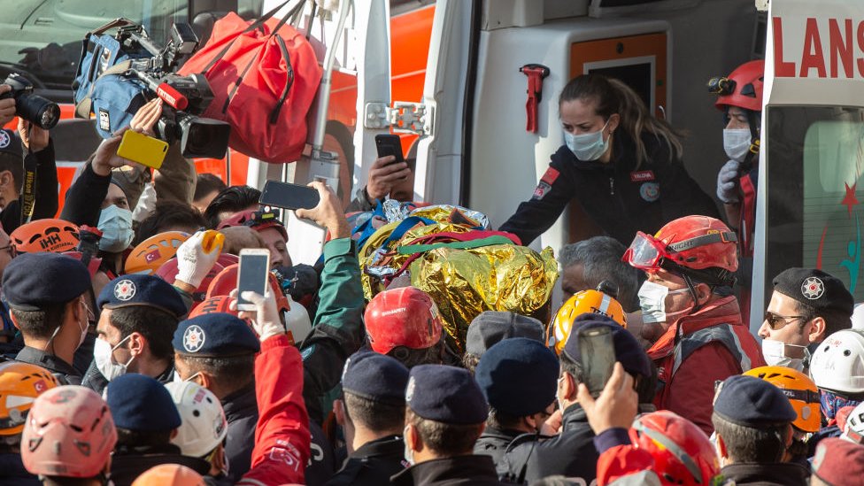 Rescue workers carry three-year-old girl toward an ambulance as they pull her out of the rubble of a building