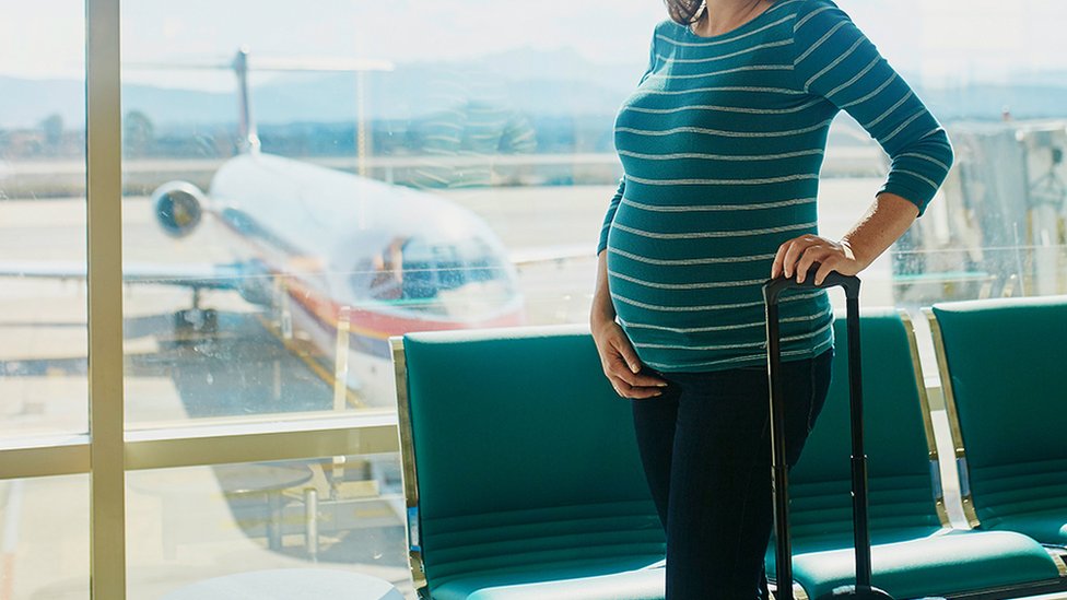 Stock image of a pregnant woman at an airport