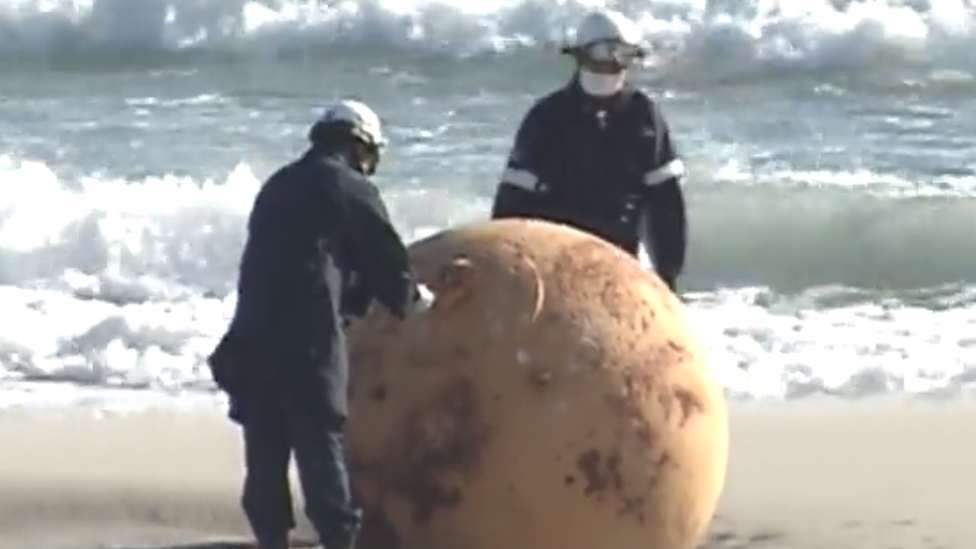 Japan: Velika misteriozna kugla pronađena na plaži zbunila meštane 1 Two police officers examine the big metal boulder found on the beach in Hamamatsu