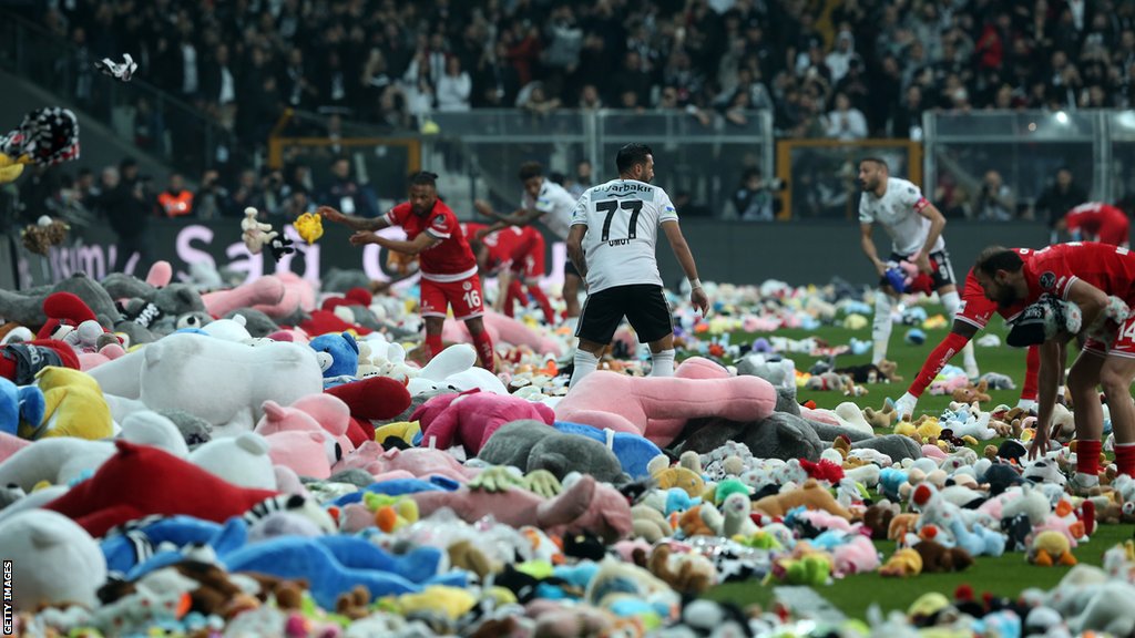 Zemljotresi u Turskoj i Siriji: Emotivne scene na stadionu - plišane igračke na terenu za decu preživelu u zemljotresu 1 Players remove Teddy bears from the pitch, thrown on to the field in support for the earthquake victim children