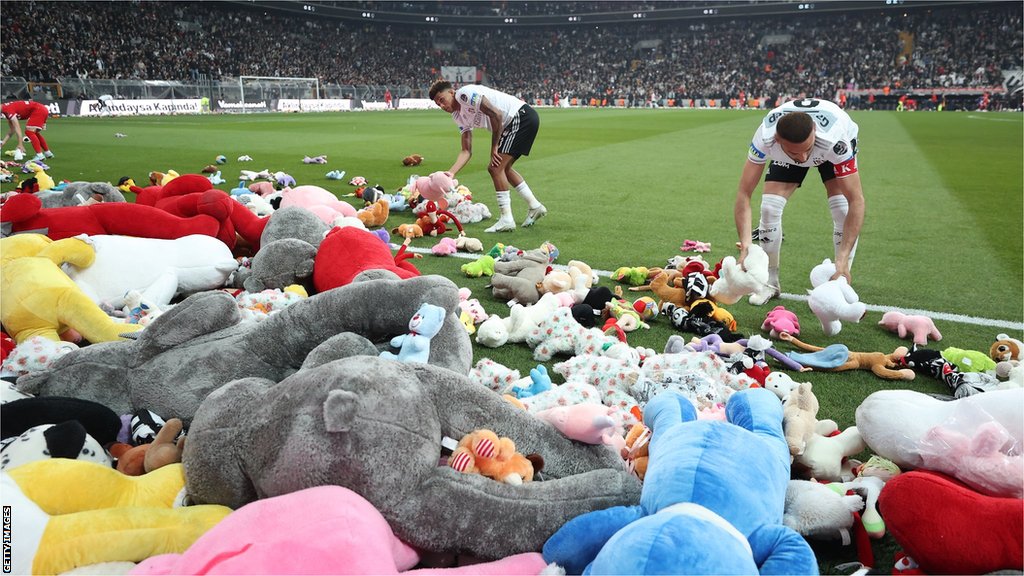 Zemljotresi u Turskoj i Siriji: Emotivne scene na stadionu - plišane igračke na terenu za decu preživelu u zemljotresu 4 Players clear the pitch after Besiktas throw Teddy bears onto the field in support for the earthquake victim children