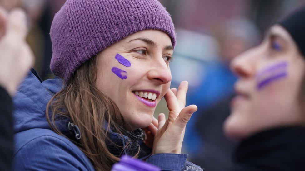 Međunarodni dan žena, Osmi mart: Istorija, marševi i proslave 4 A woman paints purple stripes on her face during a feminist women's bicycle protest on International Women's Day on March 08, 2020 in Berlin, Germany