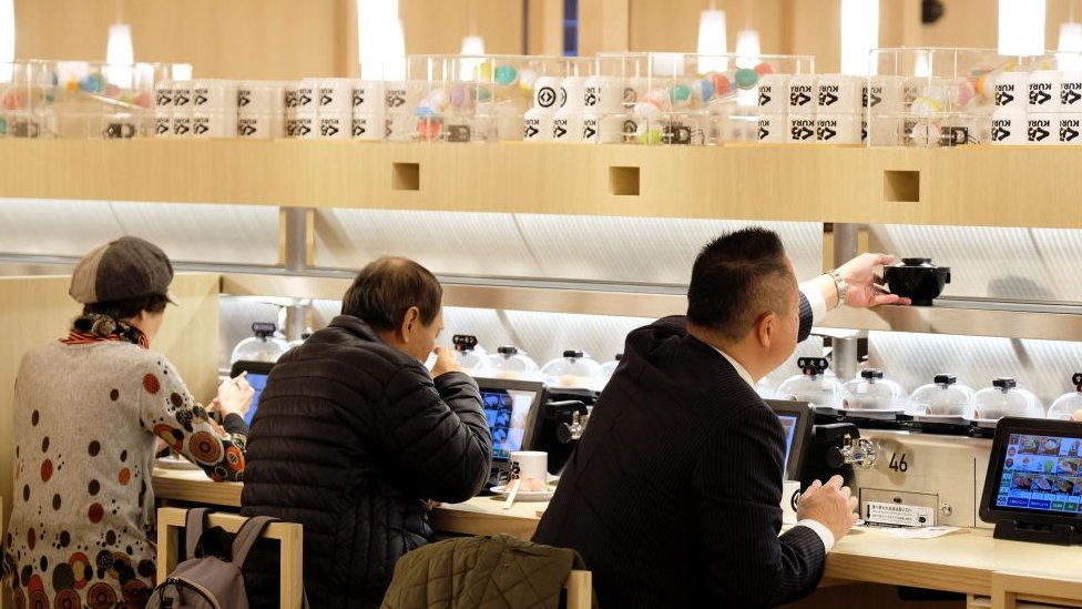 Japan i hrana: Šta je „suši teror" koji hara zemljom 1 Customers seated at a sushi conveyor belt restaurant in Tokyo