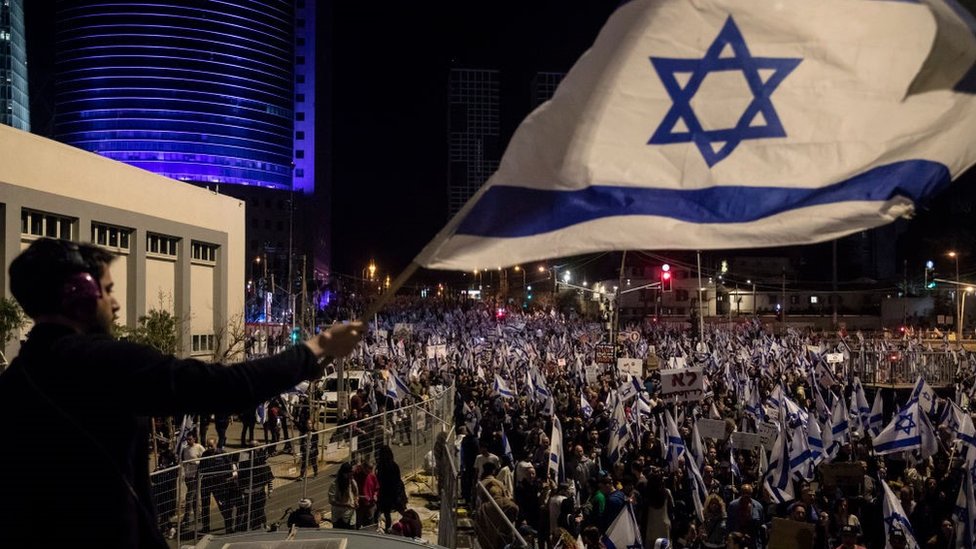 Izrael, protesti: Demonstracije širom zemlje među najmasovnijim u istoriji 1 A protester waves the Israeli flag during a massive protest against the government's judicial overhaul plan on 11 March 2023 in Tel Aviv