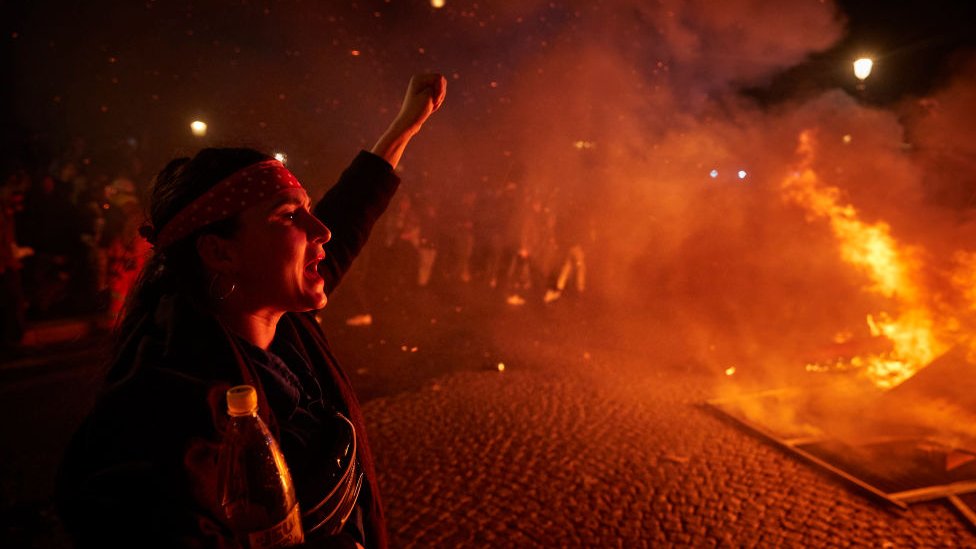 A protester chants and sings in front of a burning barricade at Place de la Concorde in Paris