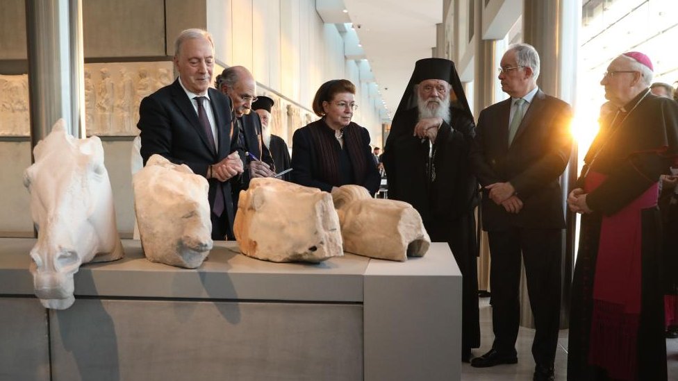 A group of Vatican and Greek officials stand near the returned marbles