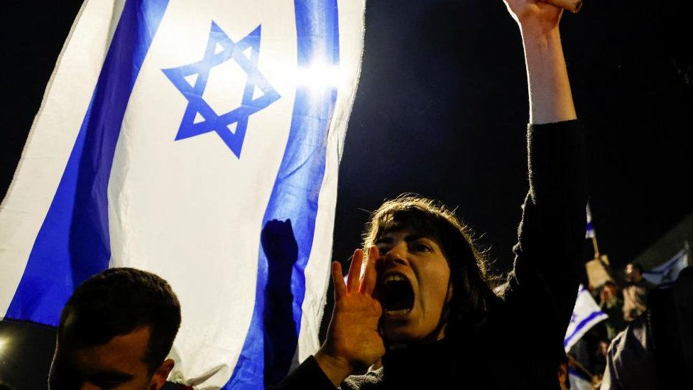 Izrael i politika: Velike demonstracije i neredi nakon pšto je Netanjahu smenio ministra odbrane 1 A woman yells while holding an Israeli flag