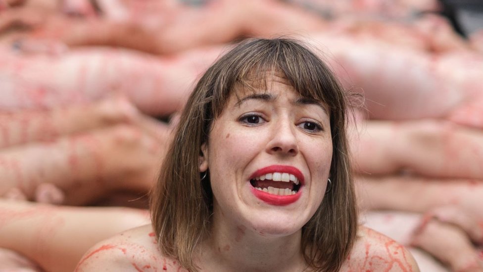 An activist naked and with paint that simulates blood lies on the ground during a protest demanding the non-use of animal skins and the closure of fur farms in Puerta del Sol, Madrid