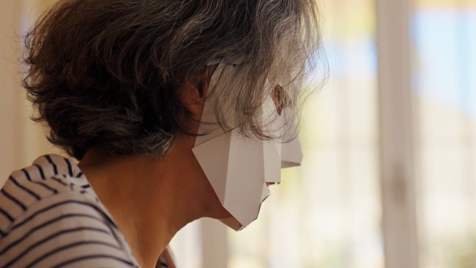 Maria, one of the ninjas, sits at her desk while wearing a paper mask