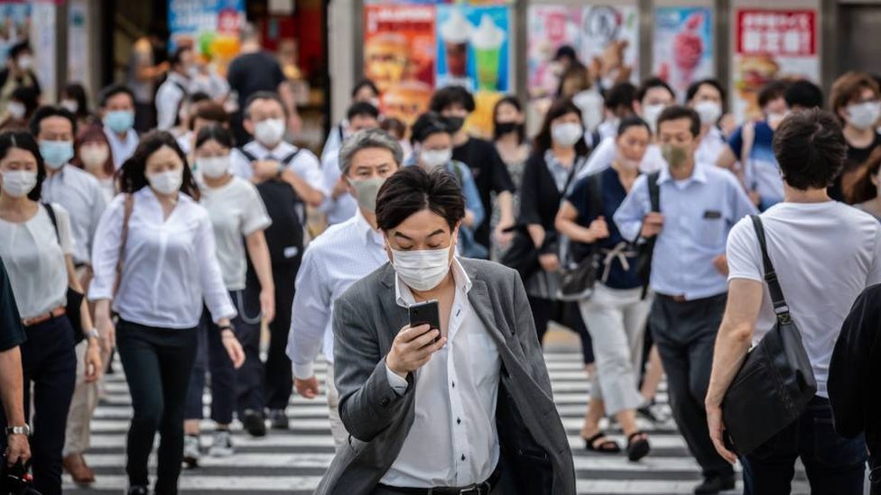 People walking on a busy street in Japan wearing face masks