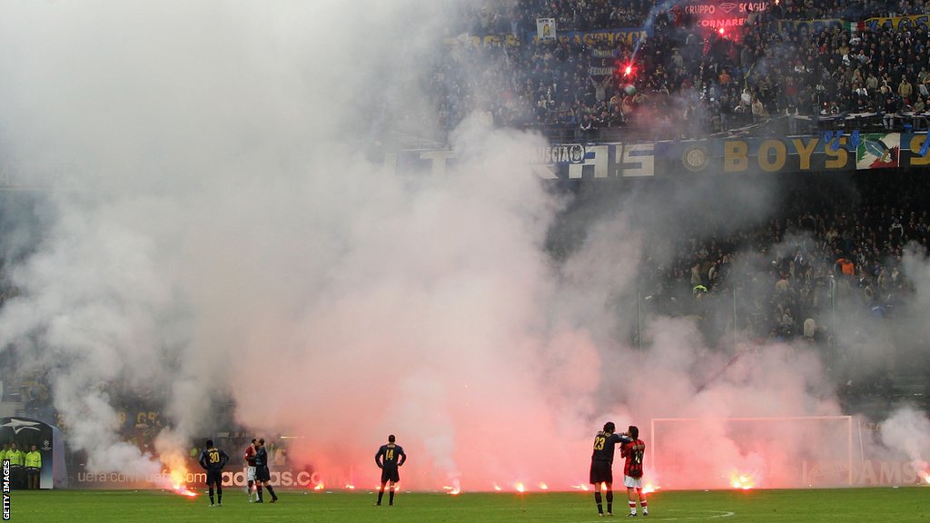 Inter, Milan i Liga šampiona: Fudbalski rat u Milanu i fotografija koja će ostati za večnost 6 Rui Costa and Marco Materazzi watch as flares fall on the pitch at the San Siro during AC Milan and Inter's 2005 Champions League quarter-final