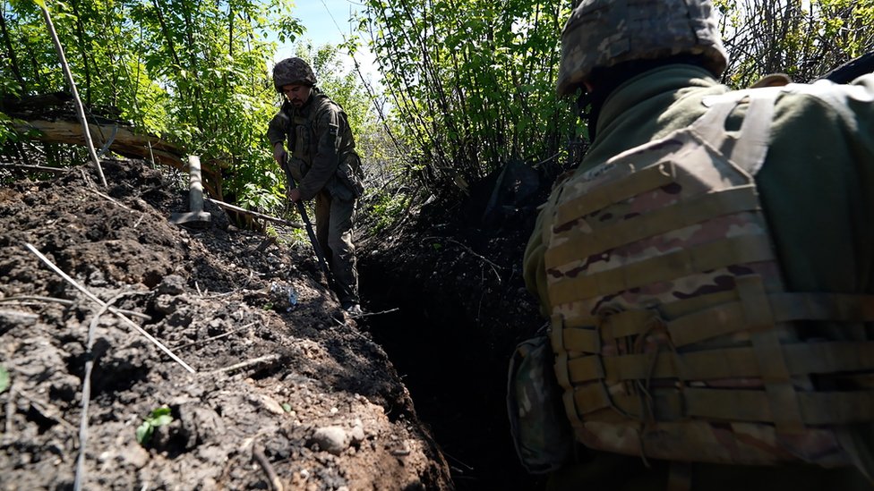 Ukrainian troops seek cover in trenches and behind the foliage of bushes on the outskirts of the city of Bakhmut