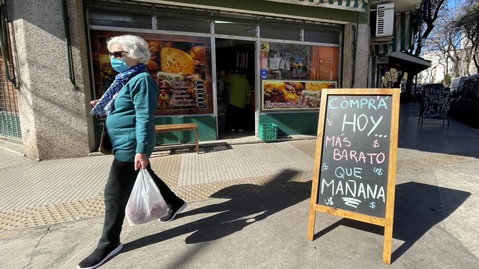 Rekordna inflacija: Pet načina na koje se Argentina bori sa krizom 1 A shopper walks past a placard that reads "Buy today, cheaper than tomorrow", outside a store, following Argentina's high inflation, as the economic crisis grips, in Buenos Aires, Argentina, July 29, 2022.