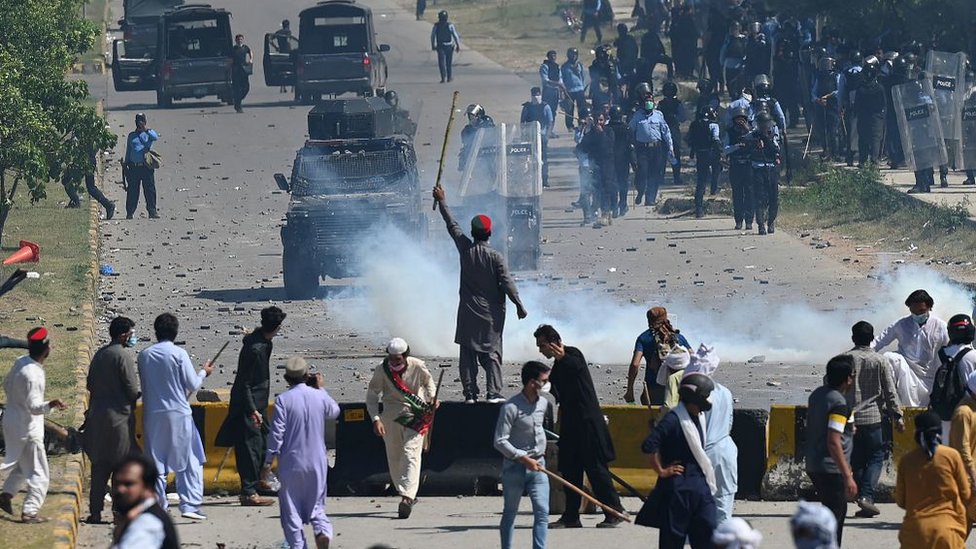 Police use teargas to disperse Pakistan Tehreek-e-Insaf (PTI) party activists and supporters (foreground) of former Pakistan's Prime Minister Imran Khan during a protest against the arrest of their leader, in Islamabad on May 10, 2023.