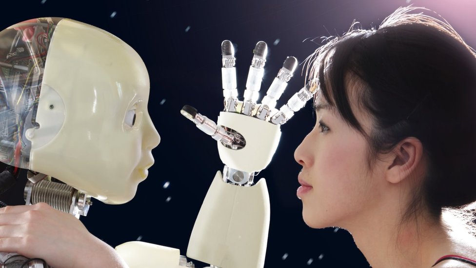 humanoidni robot drži ruku ispred lica žene koja ga gleda pravo u oči