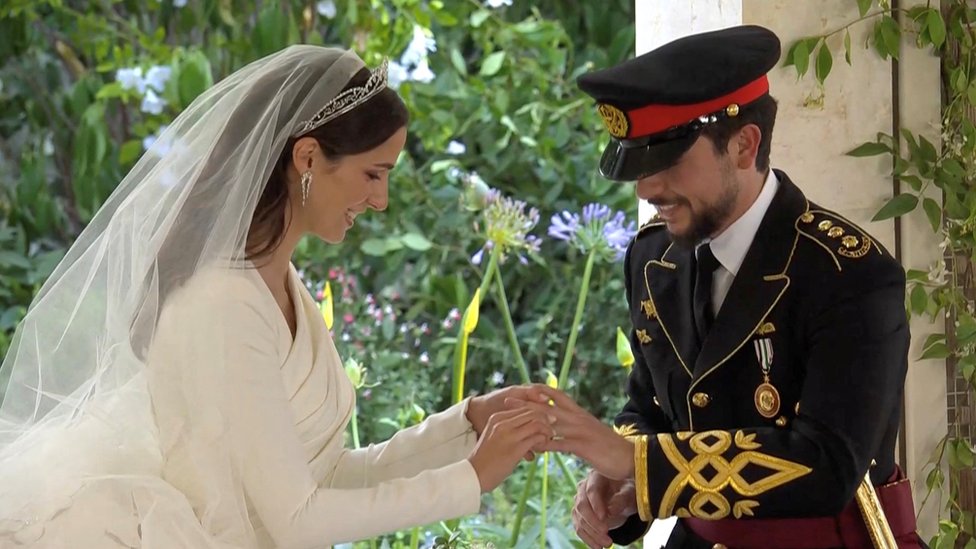 bride and groom putting wedding bands on each other's finger