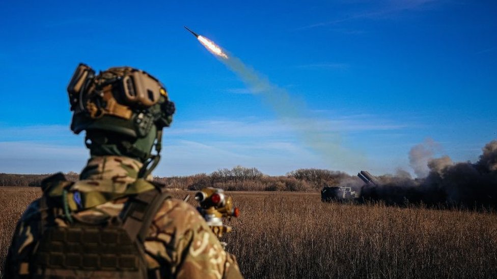 A Ukrainian soldier watches a rocket launcher firing towards Russian positions on the front line in eastern Ukraine in November