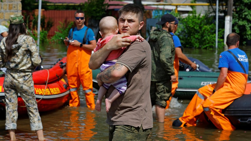 A man holds a baby in flooded Kherson