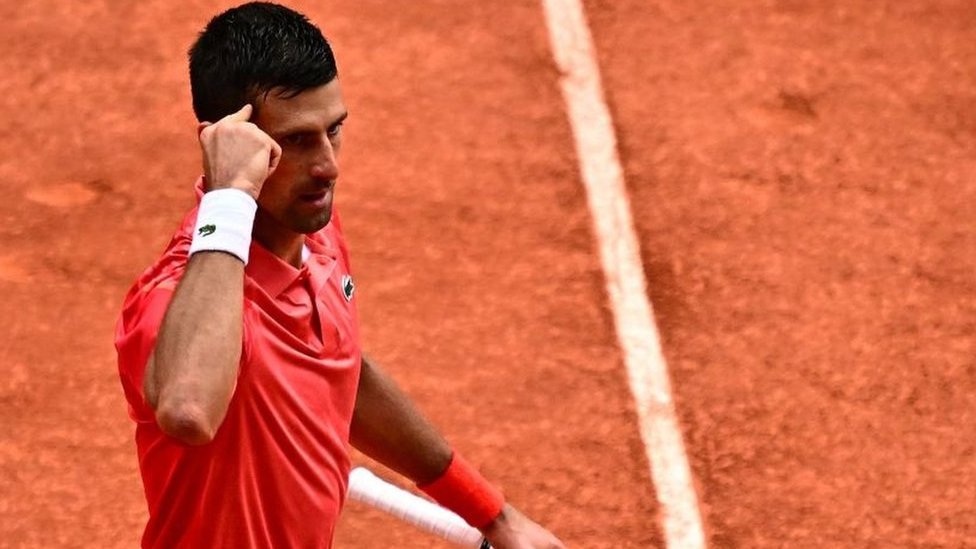 Novak Djokovic points to his temple at the French Open