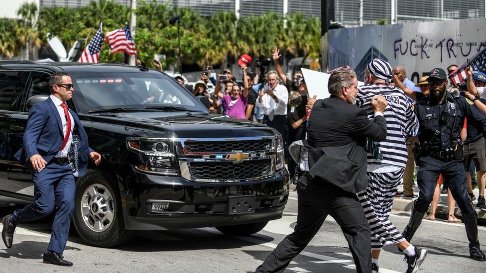 Amerika: Donald Tramp na sudu u Majamiju po optužbi za zadržavanje poverljivih dokumenata - galerija 15 A security guard grabs a man dressed as an inmate in a black-and-white striped prison-style outfit, who ran in front of Donald Trump's motorcade