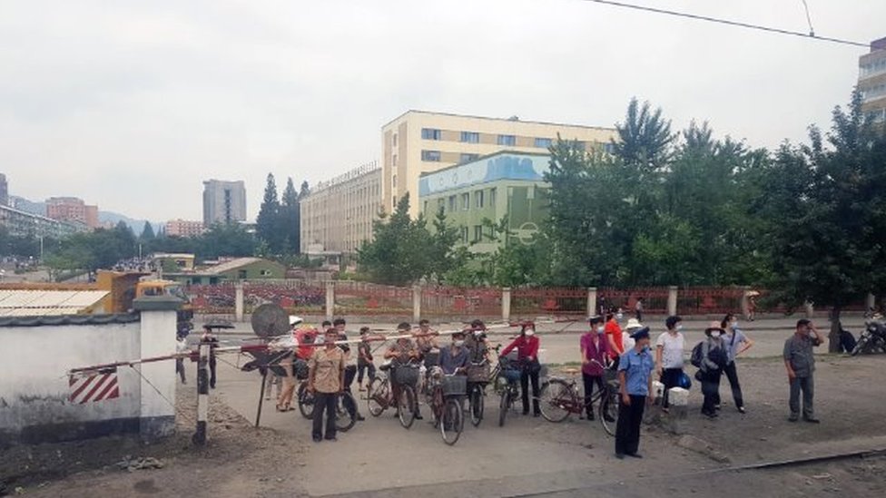 Severna Koreja iznutra: „Zaglavljeni smo ovde, čekamo da umremo“ 5 Masked citizens wait for a train to pass at a crossing in Phyongysong, North Korea