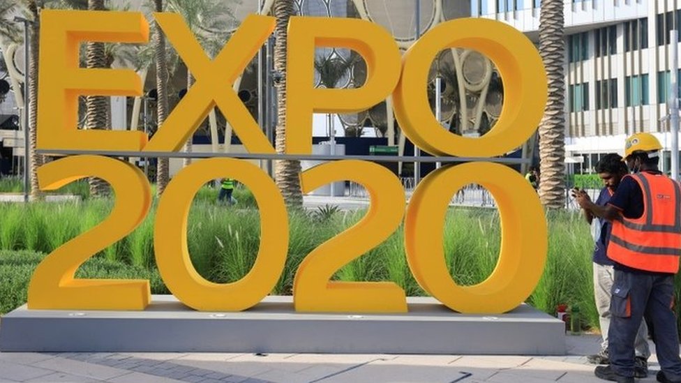 Workers stand next to an Expo 2020 sign ahead of the opening ceremony in Dubai, United Arab Emirates (30 September 2021)