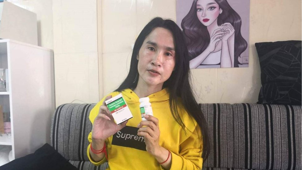 Kuy Pov holding a strip of PrEP pills