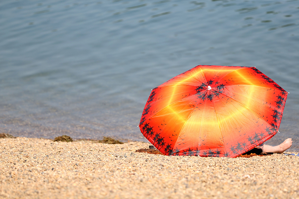 A woman rests under a parasol at the Ada lake in Belgrade, Serbia