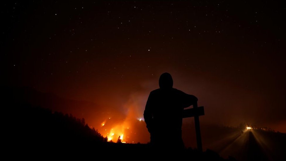 A person looks on as a forest fire burns in Tijarafe on the island of La Palma, Spain