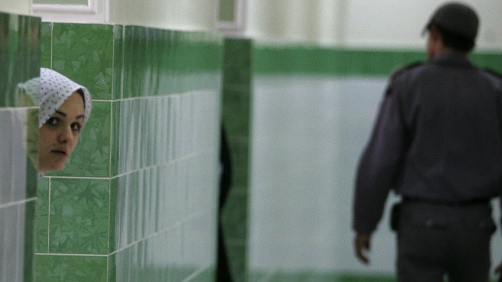 Iran i ljudska prava: Zatvorenice tvrde da su ih čuvari snimali su tokom pretresa do gole kože 3 An Iranian inmate peers from behind a wall as a guard walks by at the female section of the infamous Evin jail