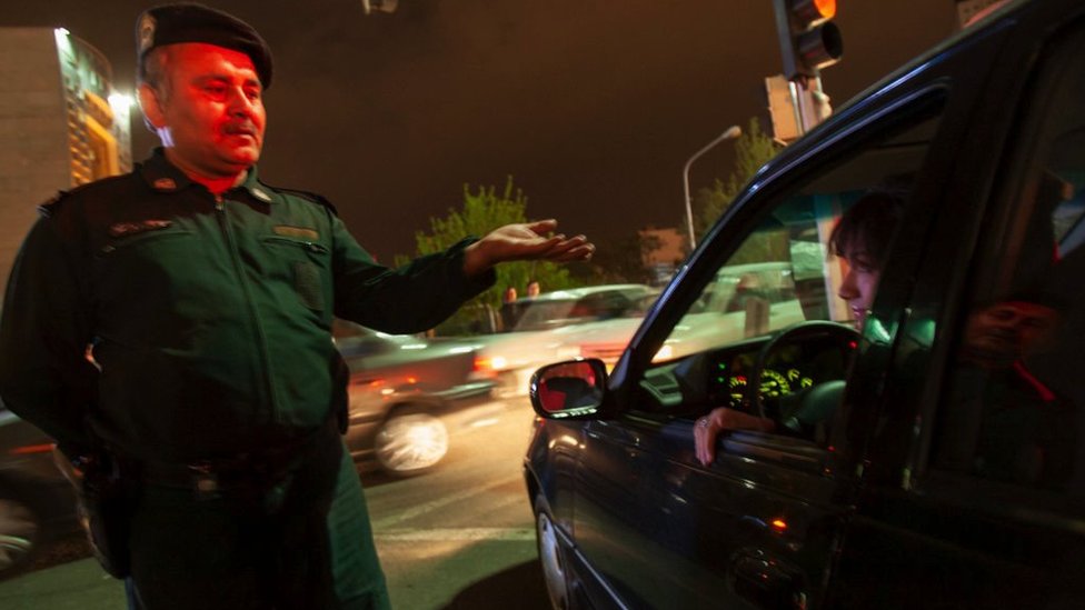 An Iranian morality policeman talks to a woman sitting in her vehicle in Tehran