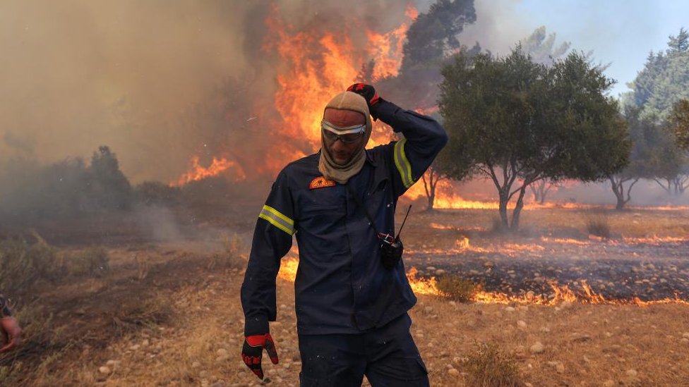 Toplotni talas ’Kerber’: Požari u Grčkoj se smiruju, evakuacija zbog eksplozija u vazduhoplovnoj bazi grčke vojske 9 A firefighter walks next to rising flames as a wildfire burns near the village of Vati, on the island of Rhodes, Greece, July 25, 2023.