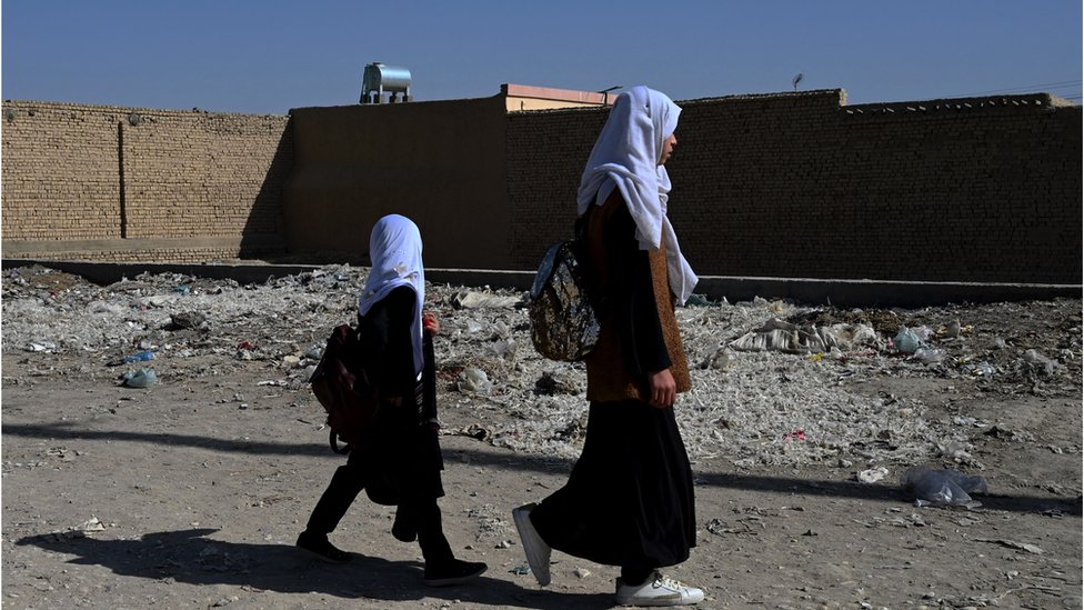 Afghan schoolgirls walk along a path as they return from school in Mazar-i-Sharif on 30 October, 2021.