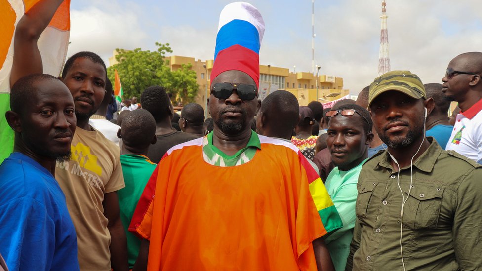 Afrika: Svrgnuti predsednik upozorava na „Vagner i širenje ruskog uticaja", Burkina Faso i Mali poručuju - „Dalje ruke od Nigera, branićemo ga" 1 A supporter of the coup wears a hat in the colours of the Russian flag during a rally in the capital on Thursday