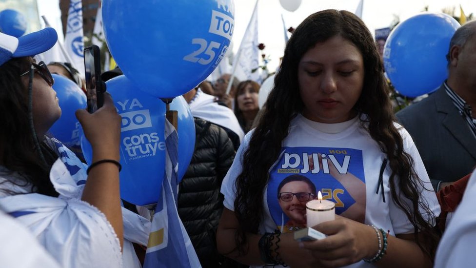 Žena drži sveću dok nosi majicu sa likom ubijenog predsedničkog kandidata Fernanda Viljavisensija