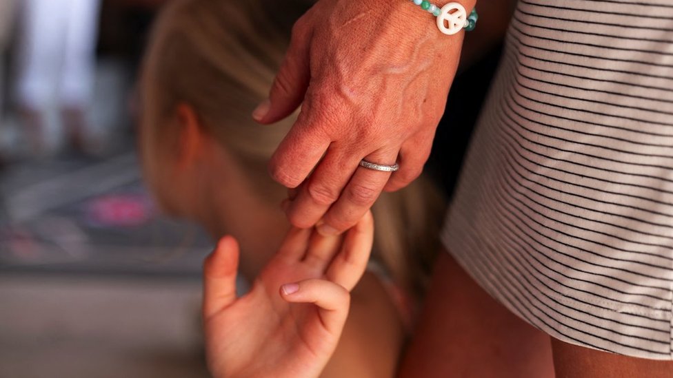 A child holds her mother's hand as members and supporters of Covenant Families for a Brighter Tomorrow pray at the entrance of the Tennessee State Capitol to call for an end to gun violence and support stronger gun laws ahead of a special session on public safety in Nashville, Tennessee, U.S., August 20, 2023. REUTERS/Cheney Orr