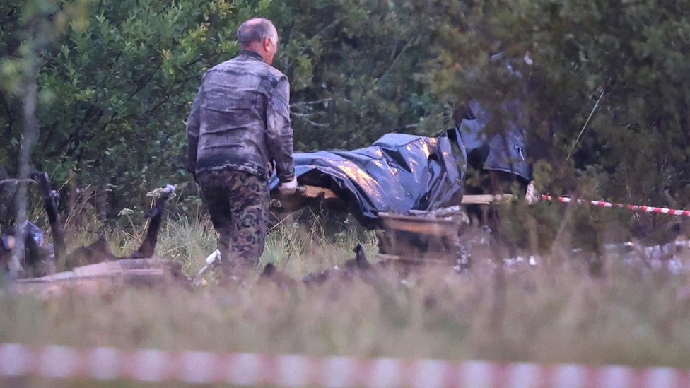 Emergency specialists carry a body bag from the wreckage of a private jet