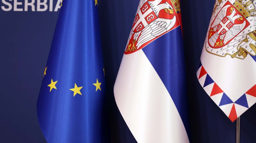 Flags of Serbia are set up next to an EU flag