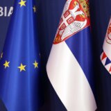 Flags of Serbia are set up next to an EU flag