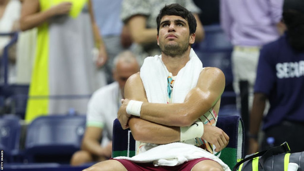 Carlos Alcaraz sits on his chair with his arms folded